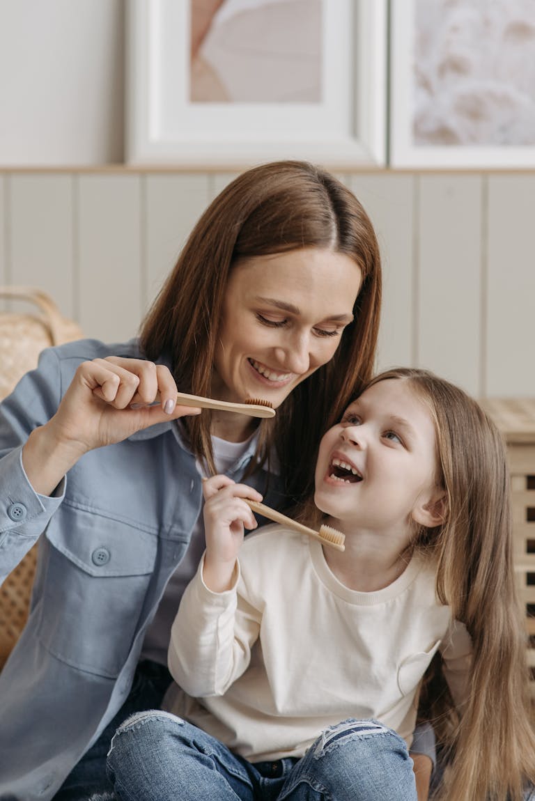 A mother and daughter enjoying quality time while brushing their teeth together indoors.