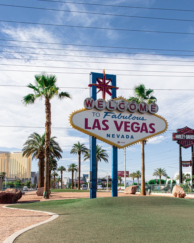 Famous Welcome to Las Vegas sign surrounded by palm trees on a sunny day.